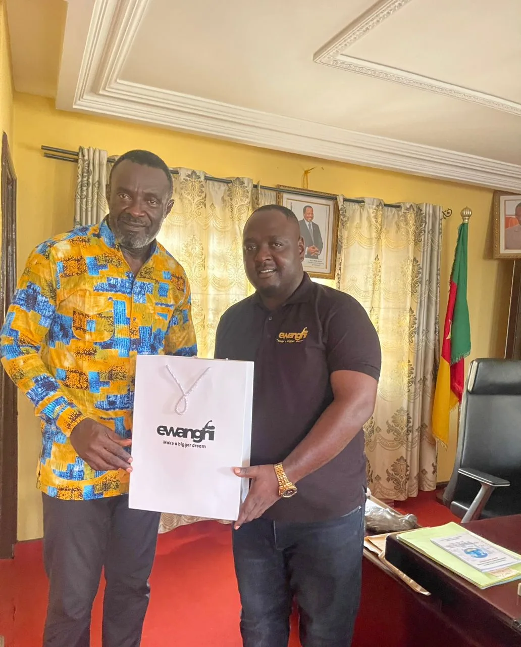 The CEO of Ewanghi Construction company, Abwa Tarkang presenting a packed containing products and services of the company to the Kumba city mayor  Gregory N.Mewanu